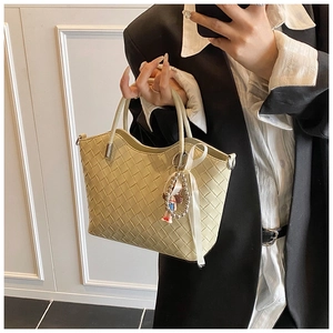 Detail of beige quilted handbag featuring wave edge opening and woven leather texture