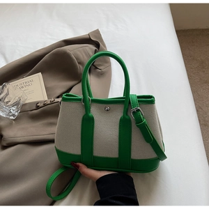 Detail of canvas and green faux leather tote bag with rivet buckle and shoulder strap