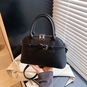 Close-up of black lychee grain leather handbag with dome shape and double zippers