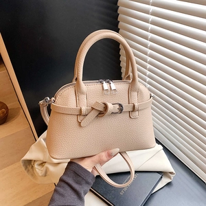 Detail view of beige pebbled leather handbag with dual zippers and decorative belt buckle