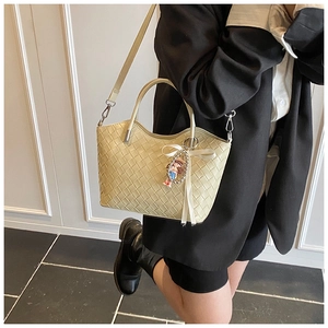 Detail of light beige woven bucket bag with diamond lattice and cute pendant