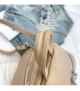 Detail of the sturdy top handle and pebble leather texture on a beige backpack