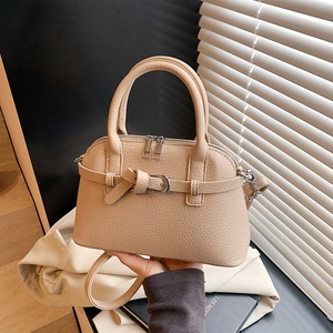Detailed macro view of the beige lychee textured leather and decorative buckle on the handbag