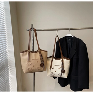 Detail view of large tote bags with cute cat patterns and Be Happy text on hanger