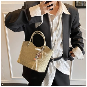 Detail of beige woven tote bag with silk bow and bear charm shown on model