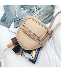 Flat lay of beige soft leather mini backpack showing capacity with iPad and sunglasses