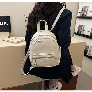 Back view of a beige pebble leather mini backpack on a model showing size and texture