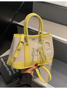 Contrast leather and canvas handbag with pearl lace bow charm on grey steps