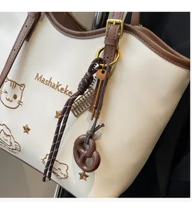 Detailed embroidery of cat head and star pattern on beige and brown leather tote bag