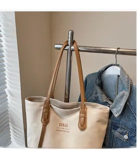 Close-up of durable canvas tote bag with brown leather handles and brand logo print