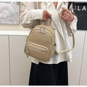 Close-up of beige pebble leather backpack featuring silver ring zippers and soft texture