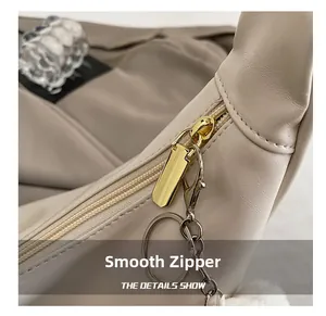 Detail view of smooth golden zipper and premium lychee texture on beige tote bag