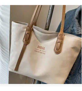 Detail of canvas tote bag with brown leather handles and SOBAG logo inscription