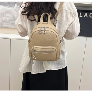 Detail of beige soft faux leather backpack featuring pebbled texture and silver metal ring