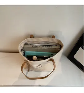 Interior view showing the large capacity of a cream canvas tote bag with brown leather handles