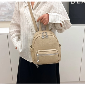 Detail of beige faux leather backpack showing fine lychee texture and silver zipper detail