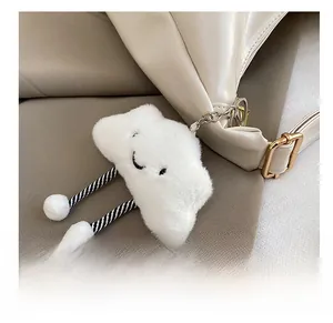 Close-up of white plush cloud charm with striped legs on a minimalist tote bag