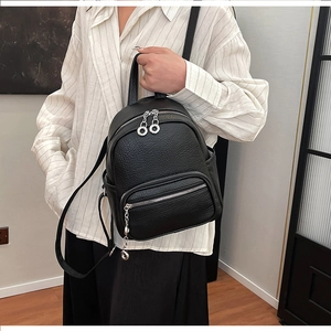 Detail view of black pebble leather mini backpack with silver metal zippers and side pockets
