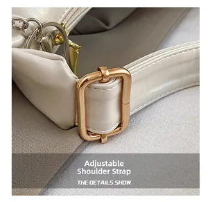 Detail view of adjustable strap with gold square buckle on textured white leather tote bag