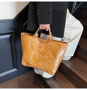 Dettaglio della borsa tote marrone con texture stropicciata e scritte TOTE BAG