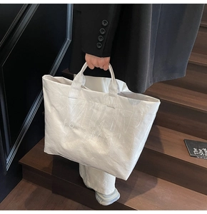 Detail der weißen Tyvek-Einkaufstasche mit Textur und TOTE BAG-Aufdruck am Griff