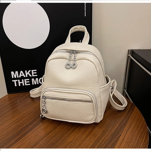 Detail of cream faux leather backpack with pebble texture and silver ring zippers