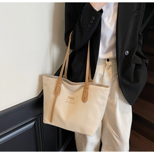 Detail of canvas tote bag with brown leather straps and SOBAG typography on casual model