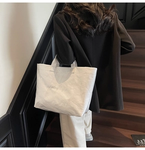 Vista dettagliata della borsa tote bianca oversize con trama a pieghe e scritte
