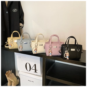 Detail view of colorful pebbled leather bucket bags with pearl and doll charms