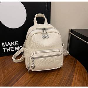 Close-up of beige lychee grain faux leather backpack with silver zippers and chain detail