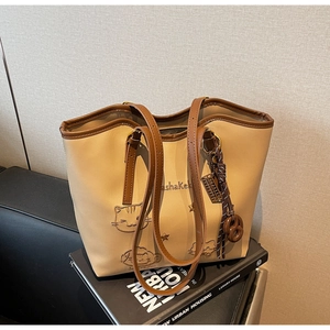 Detail of beige cartoon dog tote bag with brown braided pendant and embossed star pattern