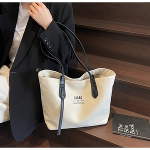 Detailed view of canvas tote bag with black leather straps and SOBAG logo text