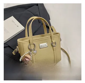 Detail of creamy yellow bucket bag with lychee grain texture and cute pearl pendant