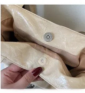 Gros plan sur la boucle magnétique argentée et coutures du sac cabas beige