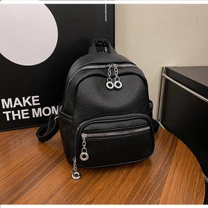 Detail of black pebbled faux leather mini backpack with silver metal zippers and ring pulls