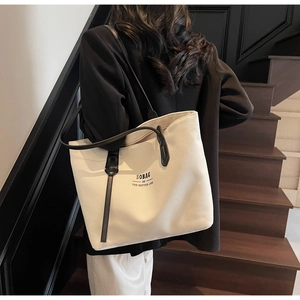 Chic cream canvas tote bag with black straps and SOBAG text worn on shoulder