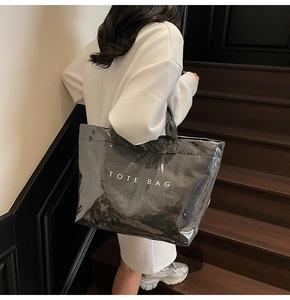 Dettaglio della borsa tote nera lucida con testo TOTE BAG bianco sulle scale