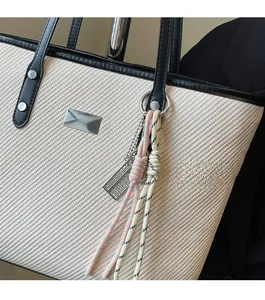 Detail of off-white twill tote bag showing black leather trim and metal JINGPIN logo