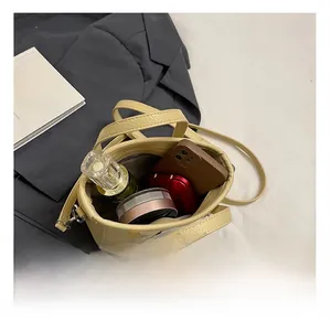Detail view of mini yellow bucket bag showing interior capacity for phone and perfume