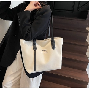 Detailed side view of off-white SOBAG canvas tote bag with black shoulder straps and text