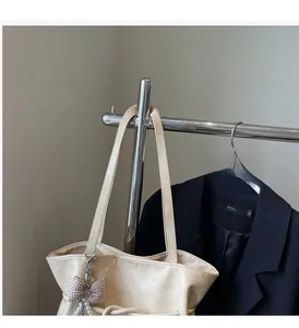 Détail du sac cabas beige avec texture en cuir plissé et pendentif perle élégant
