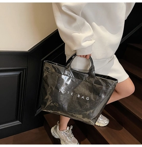 Dettaglio di una borsa tote grande in pelle verniciata nera con stampa TOTE BAG bianca