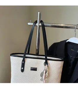 Detail of minimalist tote bag with off-white fabric, black trim and metallic logo plaque