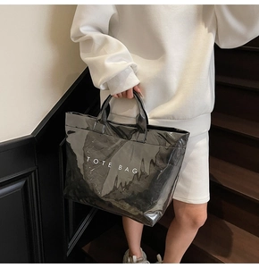 Vista macro dettagliata della borsa tote in pelle verniciata nera lucida con scritta TOTE BAG