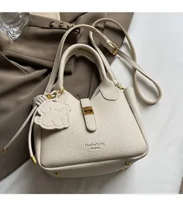 Detail of lychee pattern leather bucket bag with puppy charm and gold hardware