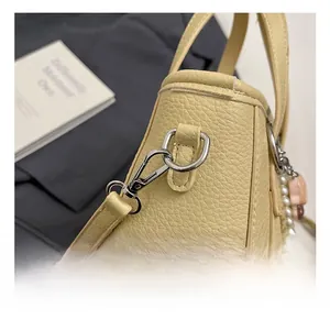 Detail of silver metal hook and cute charm on yellow lychee leather crossbody bag