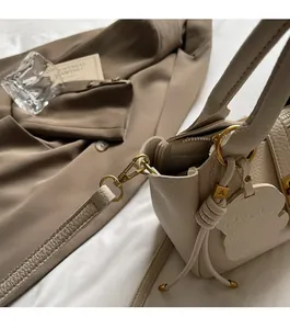 Close-up of beige lychee grain leather bucket bag with premium gold metallic hardware