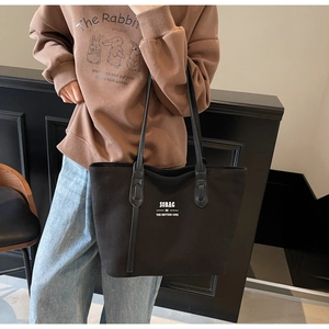 Detail of black canvas tote bag with SOBAG text and slim leather shoulder straps