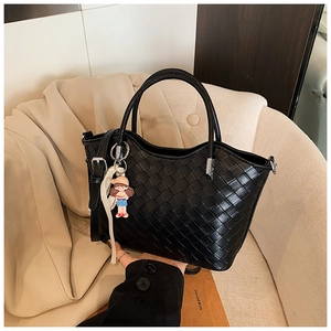 Detail of black woven leather tote featuring chic top handles and a cute cartoon charm