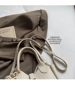 Close-up of cream lychee leather handbag with adjustable strap and golden hardware